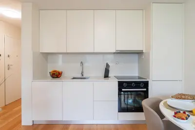 a white kitchen with a sink and a stove at Modern & Bright Flat in Cedofeita by HostWise in Porto