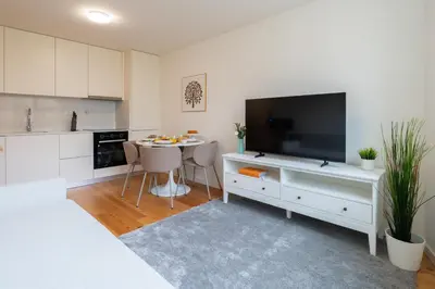 a white kitchen with a large television and a table at Modern & Bright Flat in Cedofeita by HostWise in Porto