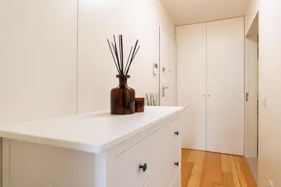 a kitchen with white cabinets and a vase with sticks in it at Modern & Bright Flat in Cedofeita by HostWise in Porto