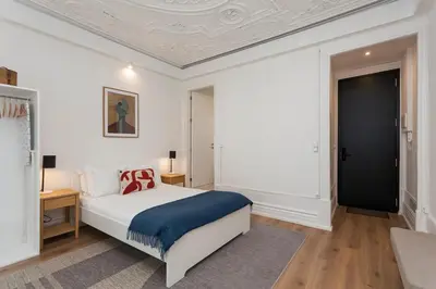 a white bedroom with a bed and a black door at Your Base Porto Art District in Porto