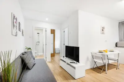 a white living room with a tv and a table at Smart Stay in Gaia | Cozy & Work-Ready in Vila Nova de Gaia