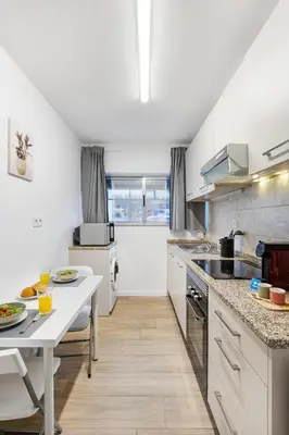 a white kitchen with a sink and a stove at Smart Stay in Gaia | Cozy & Work-Ready in Vila Nova de Gaia