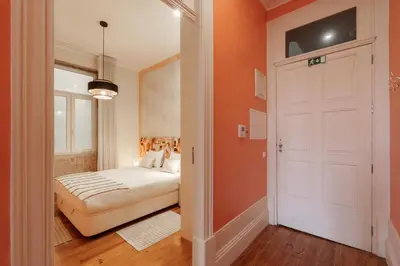 a bedroom with orange walls and a bed and a door at VIVA Breiner Chic Apartment in Porto