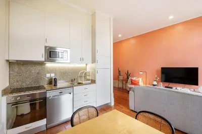 a kitchen with white cabinets and a table with chairs at VIVA Breiner Chic Apartment in Porto