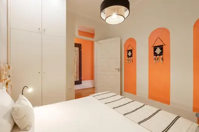 a bedroom with a white bed and an orange wall at VIVA Breiner Chic Apartment in Porto