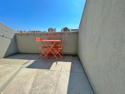 a red chair sitting on top of a balcony at Sunny rooftop duplex with elevator near iconic bridge in Vila Nova de Gaia