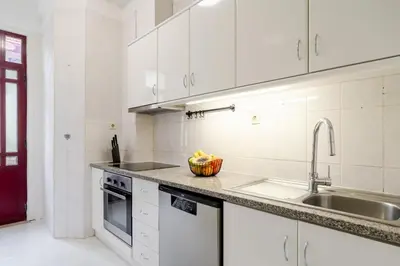 a white kitchen with a sink and a counter at Modern & Cozy Flat with Workspace by HostWise in Porto