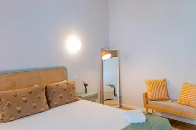 a bedroom with a bed and a chair and a mirror at VIVA Boavista Duplex Retreat in Porto