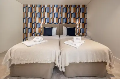 a bedroom with a large bed and two lamps at Land Roots Riverside Apartments in Vila Nova de Gaia