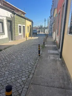 a cobblestone street with yellow and black poles on it at Cosy HouseTypical Space in Porto by Su e Luís in Porto