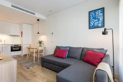 a living room with a gray couch and red pillows at Antas Park with pool and gym - to work & leisure in Porto