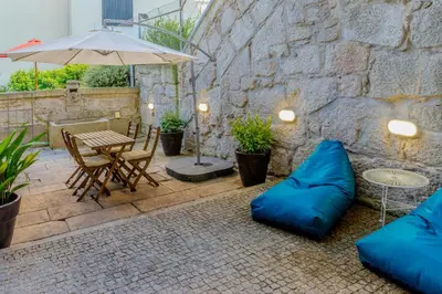 a patio with blue pillows and a table and an umbrella at VIVA República Serviced Apartment in Porto