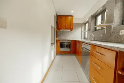 a kitchen with wooden cabinets and a white tile floor at Modern Terrace 2BD Apartment by Vacationy in Porto