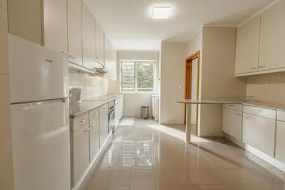 a large kitchen with white cabinets and a table at Botanic Garden Terrace Apartment by Vacationy in Porto