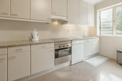 a white kitchen with white cabinets and a window at Botanic Garden Terrace Apartment by Vacationy in Porto