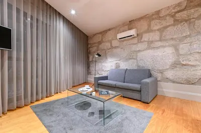 a living room with a couch and a stone wall at ON Apartments - Free Parking & Pet Friendly in Porto