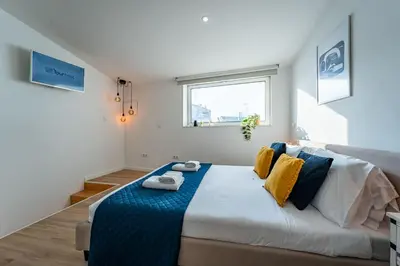 a bedroom with a large bed with yellow and blue pillows at Oporto Nura House Duplex Downtown in Porto