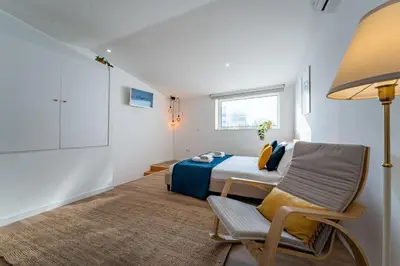 a bedroom with a bed and a chair and a lamp at Oporto Nura House Duplex Downtown in Porto