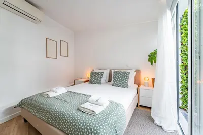 a white bedroom with a bed and a window at Oporto Nura House Duplex Downtown in Porto