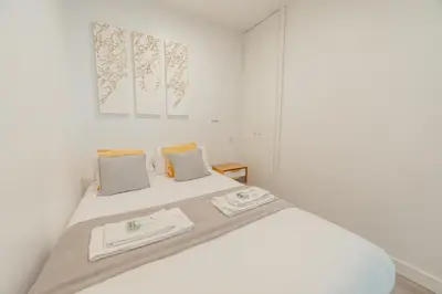 a white bedroom with a bed with two towels on it at Downtown Cosy Apartment by Vacationy in Porto