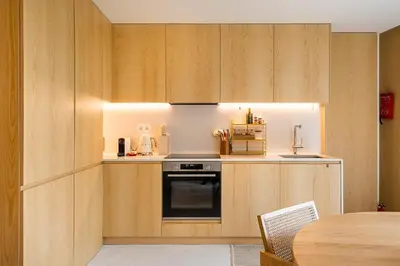 a small kitchen with wooden cabinets and a table at DPV Residences - Studio CA/C1 in Porto