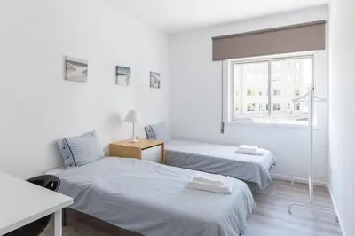 two beds in a white room with a window at Vilar 210 in Porto