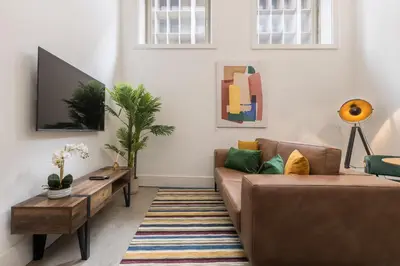 a living room with a brown couch and a tv at Design loft, Downtown Porto in Porto