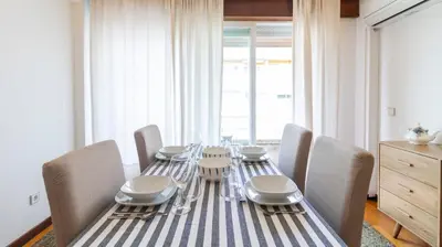 a dining table with chairs and a blue and white striped table cloth at Charmy Rodrigues Lobo Apartments in Porto