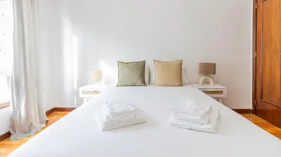 a white bed with two white towels on it at Charmy Rodrigues Lobo Apartments in Porto