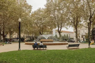two people sitting on a park bench in front of a fountain at Elegant Marques Duplex by Vacationy in Porto