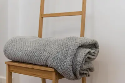a grey blanket sitting on a wooden chair at Cantinho do Porto - Metro 1 Minute Away in Porto