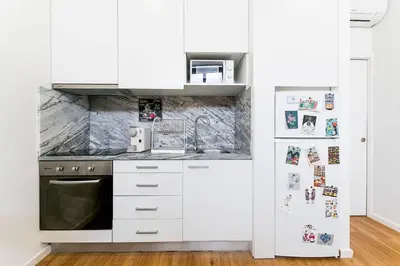 a kitchen with white cabinets and a refrigerator at Cantinho do Porto - Metro 1 Minute Away in Porto