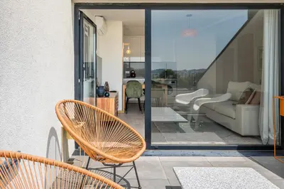 a patio with chairs and a couch on a balcony at Sunny one bedroom apartment in Porto