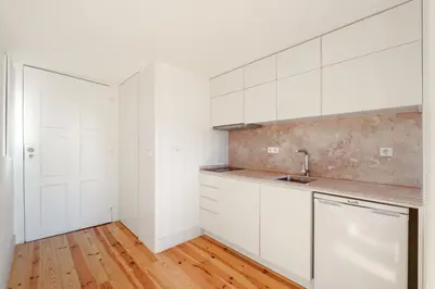 a kitchen with white cabinets and a wooden floor at VIVA Cedofeita Serviced Apartments in Porto
