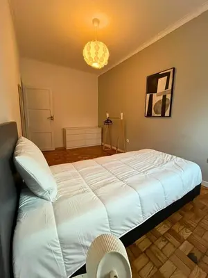 a bedroom with a large white bed and a chandelier at Good end Oporto View in Porto