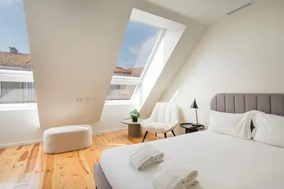 a white bedroom with a bed and a chair at GuestReady - Urban retreat in Boavista in Porto