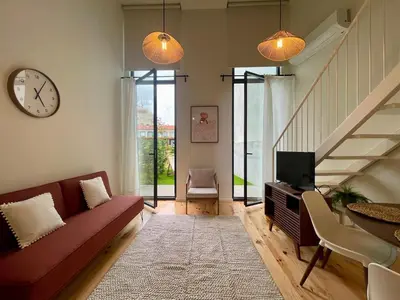 a living room with a couch and a tv and a clock at Terrace Loft near Porto Center in Porto