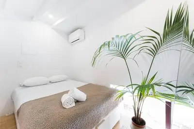 a white bedroom with a bed and a plant at Art Wine Loft with oPorto view! in Vila Nova de Gaia