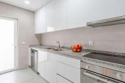 a white kitchen with a bowl of fruit on the counter at Bright & Cozy Apartment by HostWise in Vila Nova de Gaia