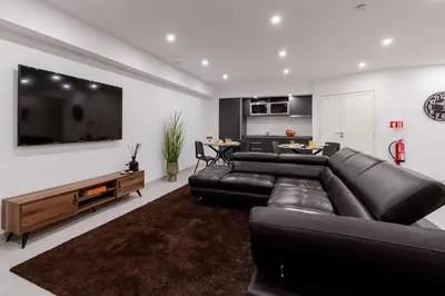 a living room with a black leather couch and a flat screen tv at Bom Sucesso Executive Suites by HostWise in Porto