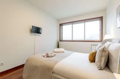 a white bedroom with a large bed and a window at Modern & Spacious Flat with Garage by HostWise in Vila Nova de Gaia