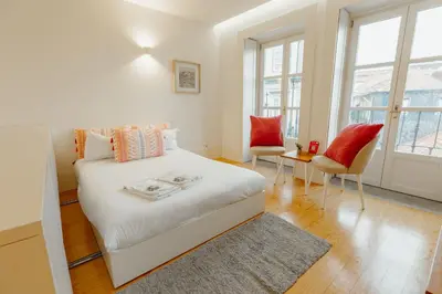 a bedroom with a white bed and two chairs at Historical Taipas Apartments by Vacationy in Porto