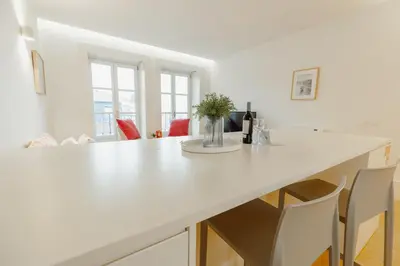 a white kitchen with a white counter and chairs at Historical Taipas Apartments by Vacationy in Porto
