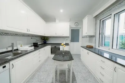 a kitchen with white cabinets and a table with a candle on it at Douro Garden Home Rooftop in Vila Nova de Gaia