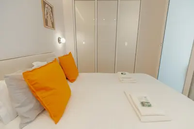 a white bed with two orange pillows on it at Bright Window Apartment by Vacationy in Porto