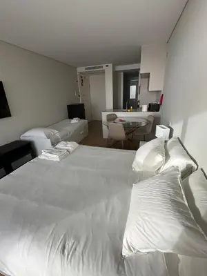 a bedroom with a large white bed and a living room at New Douro Tower 305 with shared pool and parking in Vila Nova de Gaia