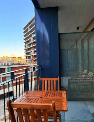 a wooden table and chairs on a balcony at New Douro Tower 206 with shared pool and parking in Vila Nova de Gaia