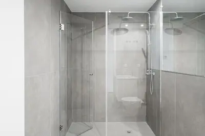 a bathroom with a glass shower with a toilet at Spacious Studio Apartment in Porto