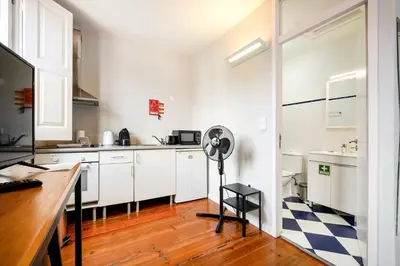 a kitchen with white cabinets and a fan in it at GuestReady - Cosme Heritage Apartments in Porto