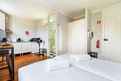 a bedroom with two white beds and a kitchen at GuestReady - Cosme Heritage Apartments in Porto